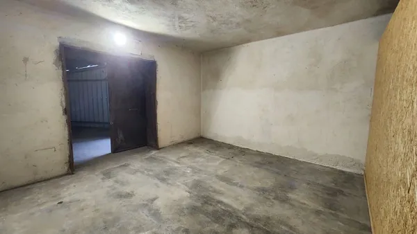 Vue intérieure d’un box, avec sa porte métallique et une cloison en bois