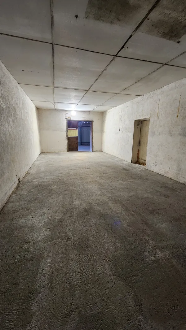 Couloir éclairé desservant les box, avec une porte au fond