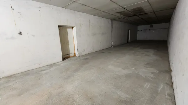 Grand espace de stockage vide, avec murs maçonnés et sol en béton